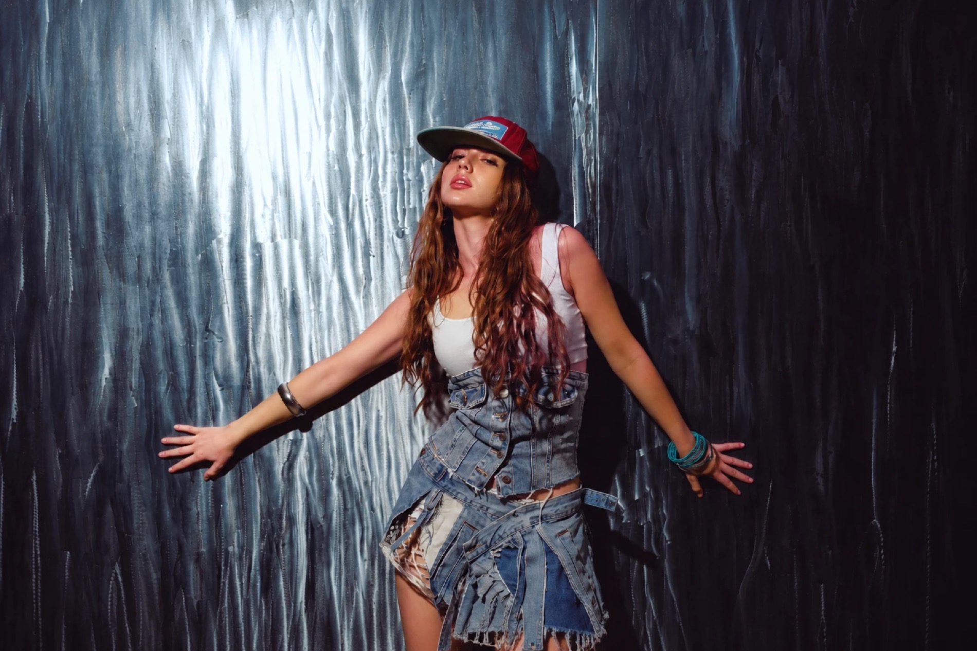 Jelexy standing with arms open against a metallic wall